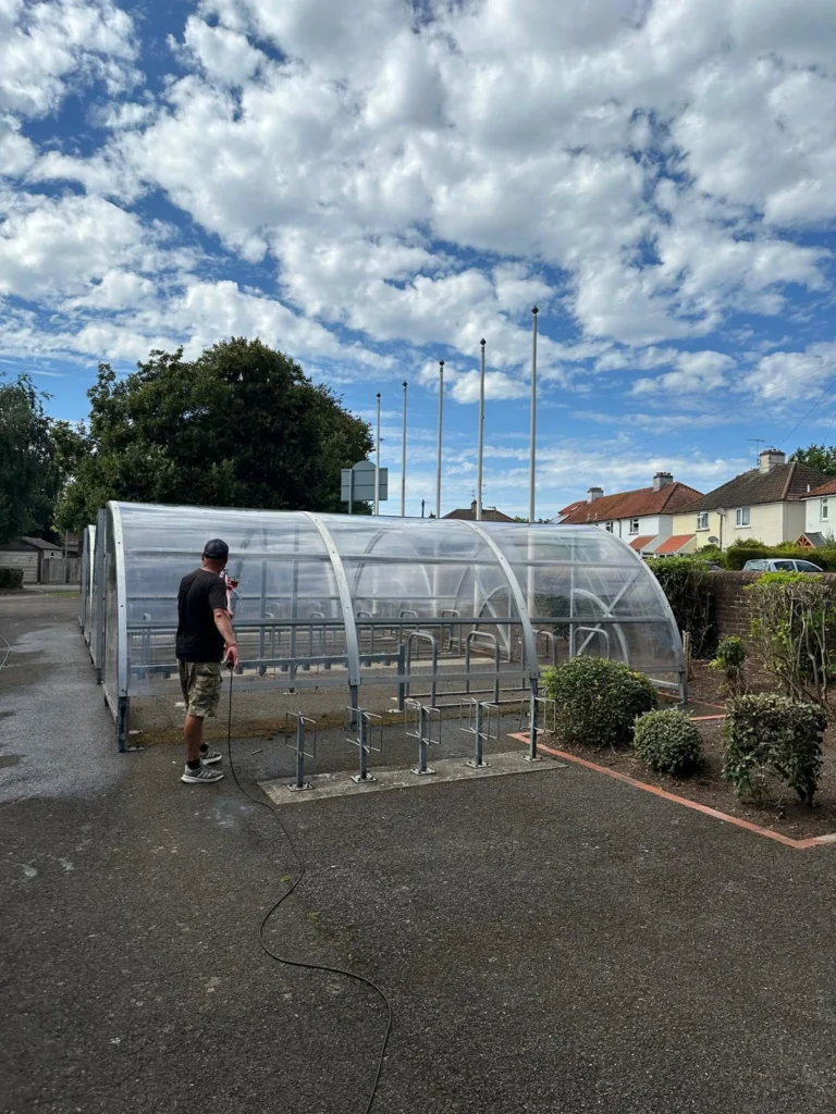 Cleaning glass on school bike shed.